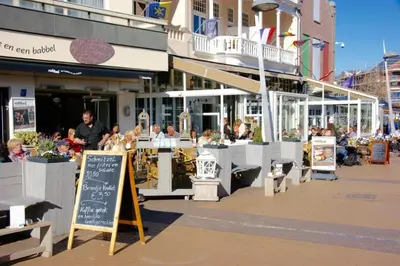 a group of people sitting at tables outside a restaurant at Nina's Beach House 1 