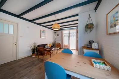 a living room with a wooden table and blue chairs at Nina's Beach House 1 