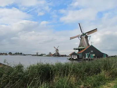 two windmills on the water with a house in the foreground at Lowlander BnB in Heemskerk