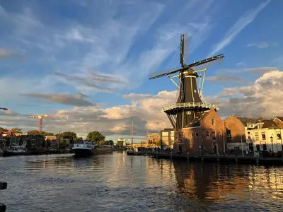 a windmill sitting in the water next to a river at Lowlander BnB in Heemskerk