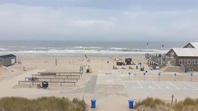 a beach with benches and a building and the ocean at Ferienhaus-Naumann-Kreetz in Burgerbrug