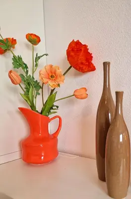 three vases sitting on a counter with flowers in them at Studio Noordzee in Egmond aan Zee