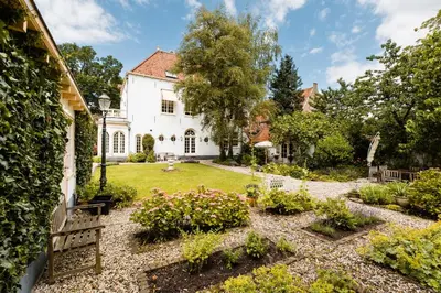 an exterior view of a white house with a garden at Fortuna Spinoza in Monnickendam