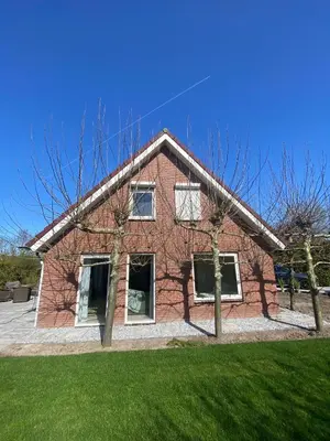 a red brick house with trees in front of it at Luxurious Family Villa with sauna big garden and jacuzzi in Zeewolde