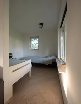 a small room with two beds and a window at Luxurious Family Villa with sauna big garden and jacuzzi in Zeewolde