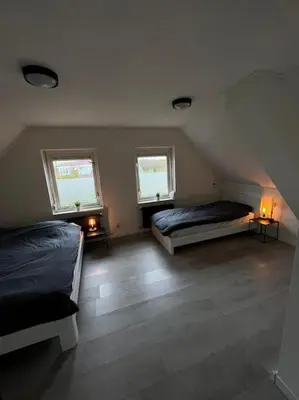 a attic bedroom with two beds and two windows at Luxurious Family Villa with sauna big garden and jacuzzi in Zeewolde