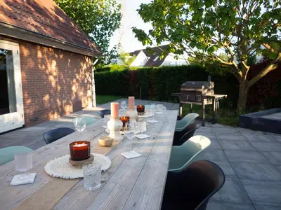 a long wooden table with chairs and candles on it at Luxurious Family Villa with sauna big garden and jacuzzi in Zeewolde