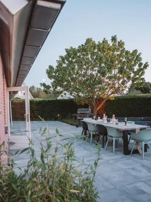 a patio with a table and chairs and a tree at Luxurious Family Villa with sauna big garden and jacuzzi in Zeewolde