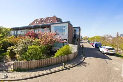 a house on the side of a road with a fence at Chapeau apartment in Zandvoort