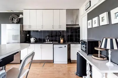 a kitchen with white cabinets and a table with chairs at Chapeau apartment in Zandvoort