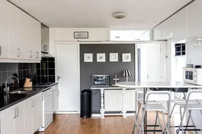 a kitchen with white cabinets and a table and chairs at Chapeau apartment in Zandvoort