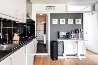 a kitchen with white cabinets and a counter with a microwave at Chapeau apartment in Zandvoort