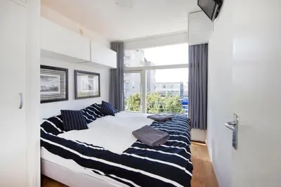a bedroom with a bed with striped pillows and a window at Chapeau apartment in Zandvoort