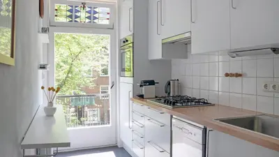 a white kitchen with a sink and a window at Authentic Amsterdam Bed and Breakfast Rai in Amsterdam