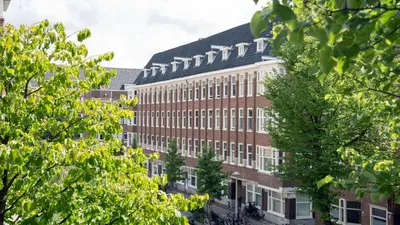 a large brick building with trees in front of it at Authentic Amsterdam Bed and Breakfast Rai in Amsterdam