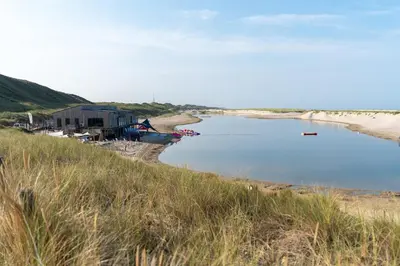 a beach with a house next to a body of water at Park Heerehof in Schoorl