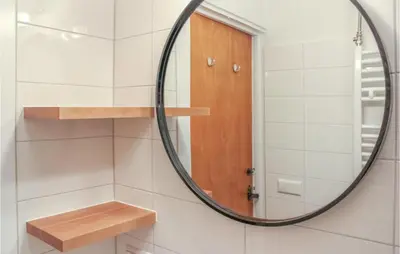 a bathroom with a round mirror and a wooden door at De Tuimelaar in Bergen aan Zee