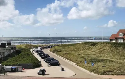 a row of cars parked on a road next to the beach at De Tuimelaar in Bergen aan Zee