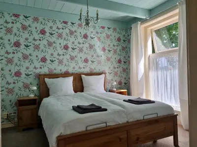 a bedroom with a bed with a floral wallpaper at Het Voorhuis boerderij Hoeve Vrede Best in Weesp