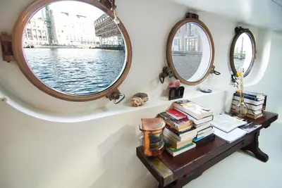 a table with books and two mirrors on a boat at Najade Eco Houseboat in Amsterdam