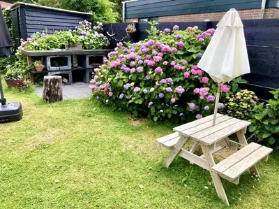 an umbrella sitting next to a bench in a garden at Holiday home Beachy Days near ocean & lake in Noordwijkerhout