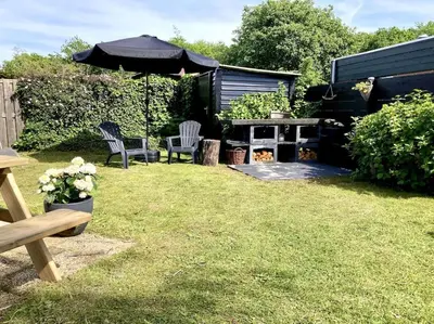 a backyard with two chairs and an umbrella at Holiday home Beachy Days near ocean & lake in Noordwijkerhout