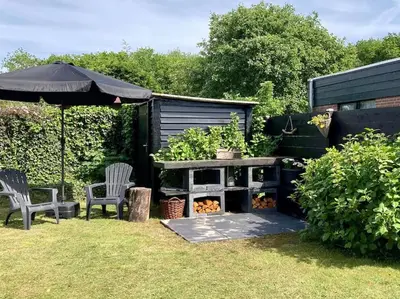 a garden with a table and two chairs and an umbrella at Holiday home Beachy Days near ocean & lake in Noordwijkerhout