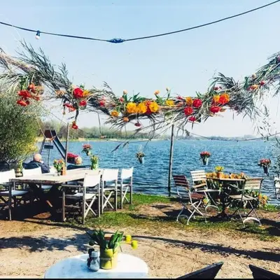 a group of tables and chairs next to a body of water at Holiday home Beachy Days near ocean & lake in Noordwijkerhout