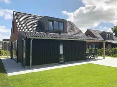 a green house with a gambrel roof at Bungalow 74 op Recreatiepark De Wielen in Sint Maarten