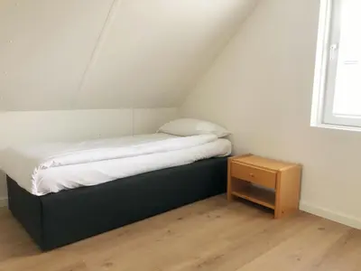 a small bed in a room with a small table at Bungalow 74 op Recreatiepark De Wielen in Sint Maarten