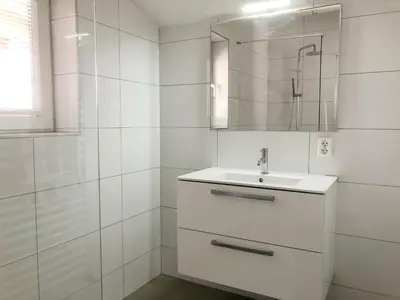 a white bathroom with a sink and a mirror at Bungalow 74 op Recreatiepark De Wielen in Sint Maarten