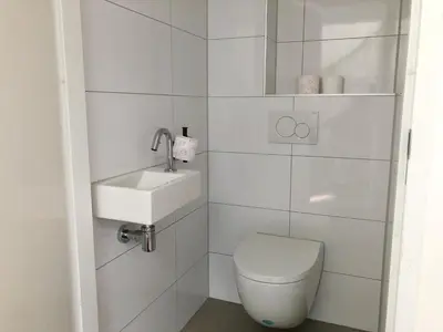a white bathroom with a toilet and a sink at Bungalow 74 op Recreatiepark De Wielen in Sint Maarten