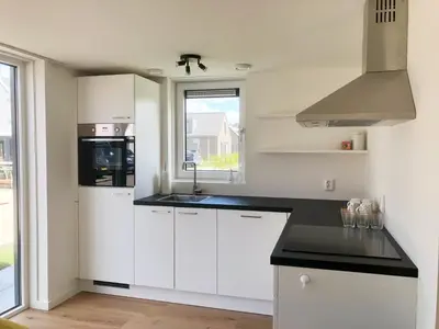 a kitchen with white cabinets and a black counter top at Bungalow 74 op Recreatiepark De Wielen in Sint Maarten