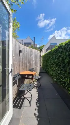 a table and bench on a sidewalk next to a fence at Koninginnehuis 35 in Zandvoort