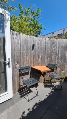 a picnic table and two chairs and a wooden fence at Koninginnehuis 35 in Zandvoort