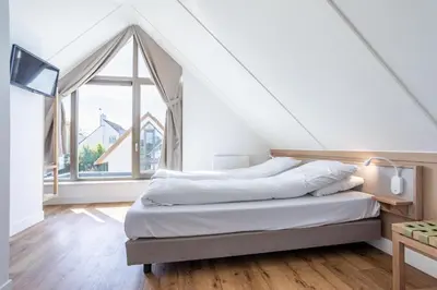 a bedroom with a bed and a large window at Duyndomein Noordwijk in Noordwijk