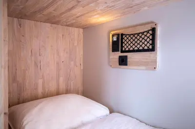 a small room with a bed and a wooden wall at The Bee Hostel in Amsterdam