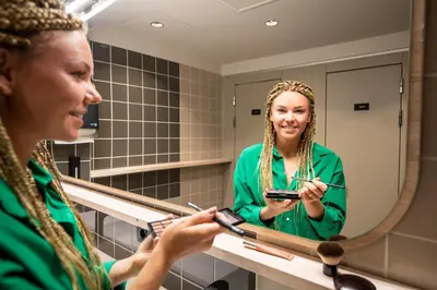a woman brushing her teeth in front of a mirror at The Bee Hostel in Amsterdam