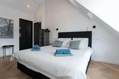 a bedroom with a large white bed with blue towels on it at Raam Studio's in Amsterdam