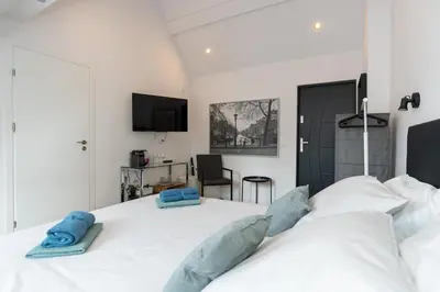 a bedroom with a large white bed with blue pillows at Raam Studio's in Amsterdam