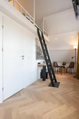 a loft with a ladder in the middle of a room at Raam Studio's in Amsterdam