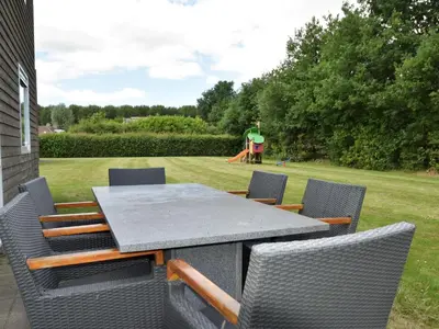 a table and chairs with a playground in the background at Holiday Home in Flevoland with Pool in Zeewolde