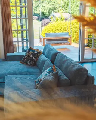 a blue couch in a living room with a large window at Buitenliefde, romantisch verblijf voor 2 personen in Heiloo