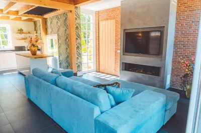 a blue couch in a living room with a fireplace at Buitenliefde, romantisch verblijf voor 2 personen in Heiloo