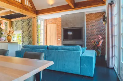 a living room with a blue couch and a tv at Buitenliefde, romantisch verblijf voor 2 personen in Heiloo