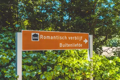 a brown street sign in front of a bush at Buitenliefde, romantisch verblijf voor 2 personen in Heiloo