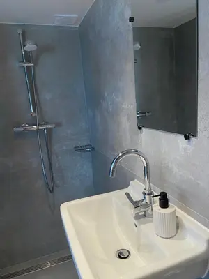 a bathroom with a sink and a shower with a mirror at The Lighthouse Cabin in Noordwijk