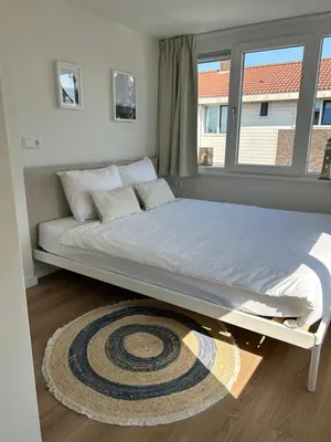 a large bed in a room with a window at Have a nice stay! - Paris Plage - volledig vernieuwd, free parking in Noordwijk aan Zee