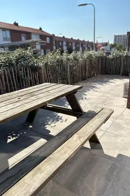 a wooden picnic table sitting on a sidewalk next to a fence at Have a nice stay! - Paris Plage - volledig vernieuwd, free parking in Noordwijk aan Zee