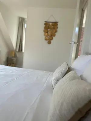 a bedroom with a white bed with a rack of wine bottles at Have a nice stay! - Paris Plage - volledig vernieuwd, free parking in Noordwijk aan Zee